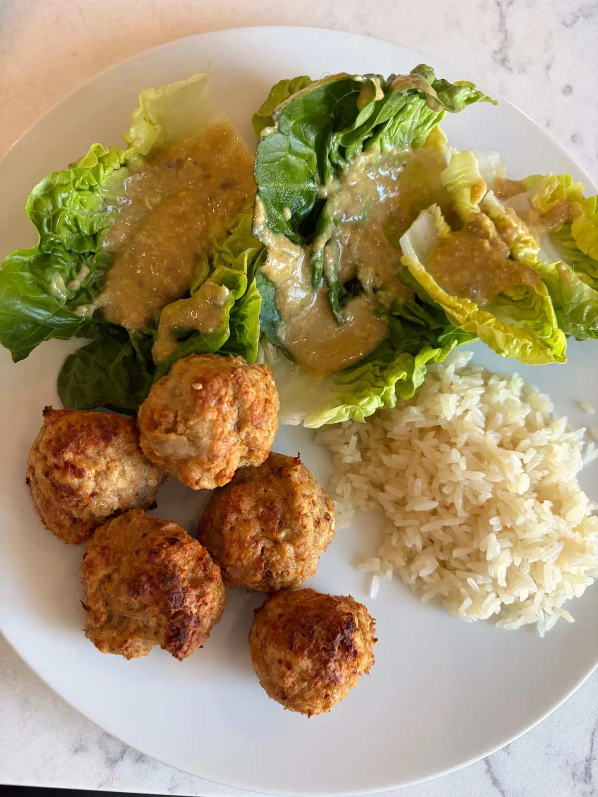Logged meal photo: chicken meatballs, rice, and Caesar salad on a white plate